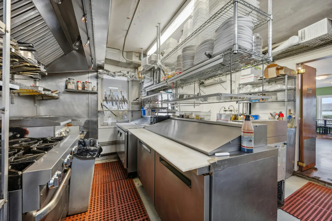 Cucina professionale in acciaio con fornelli e scaffali