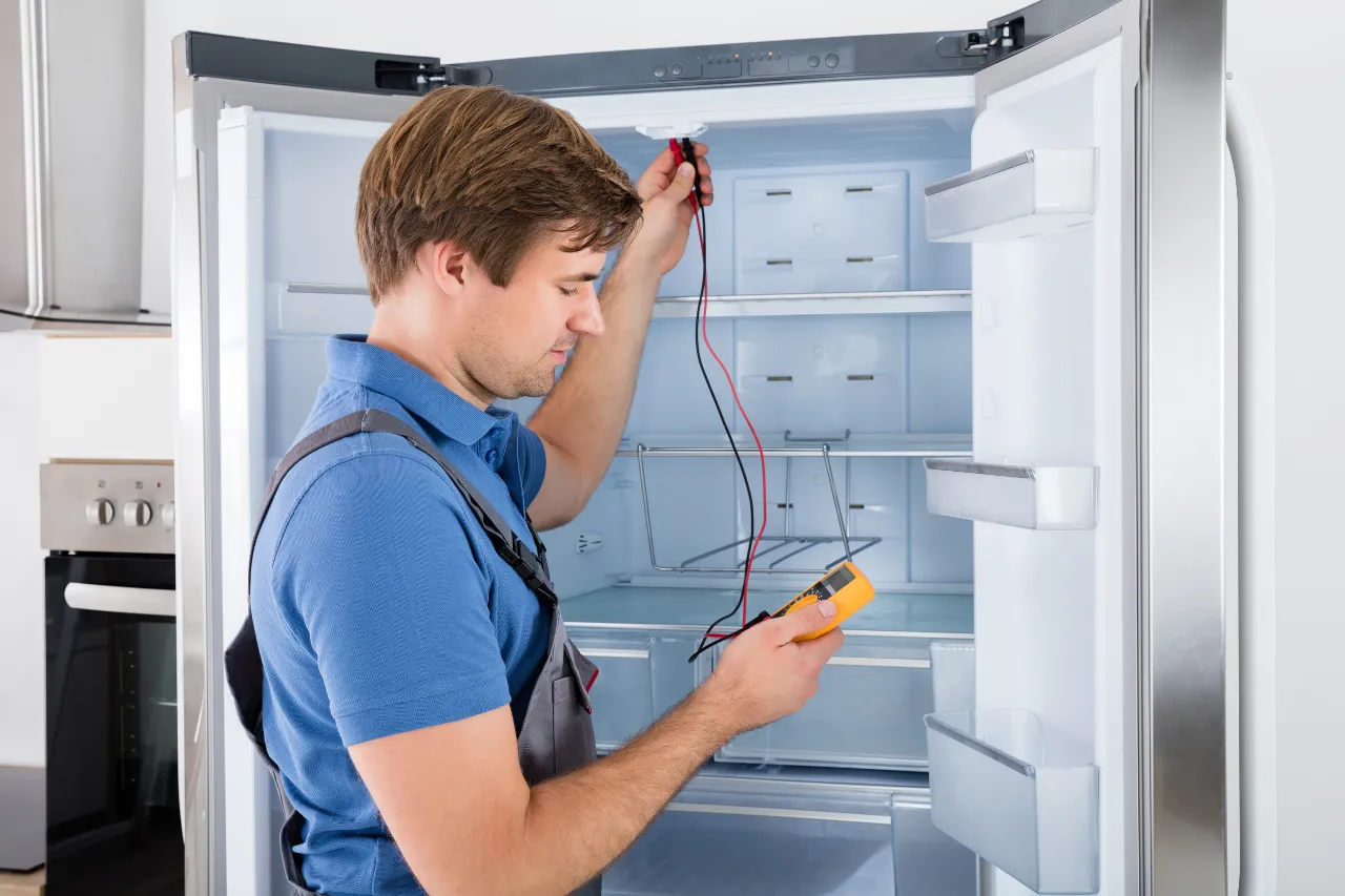 Tecnico controlla un frigorifero con multimetro digitale