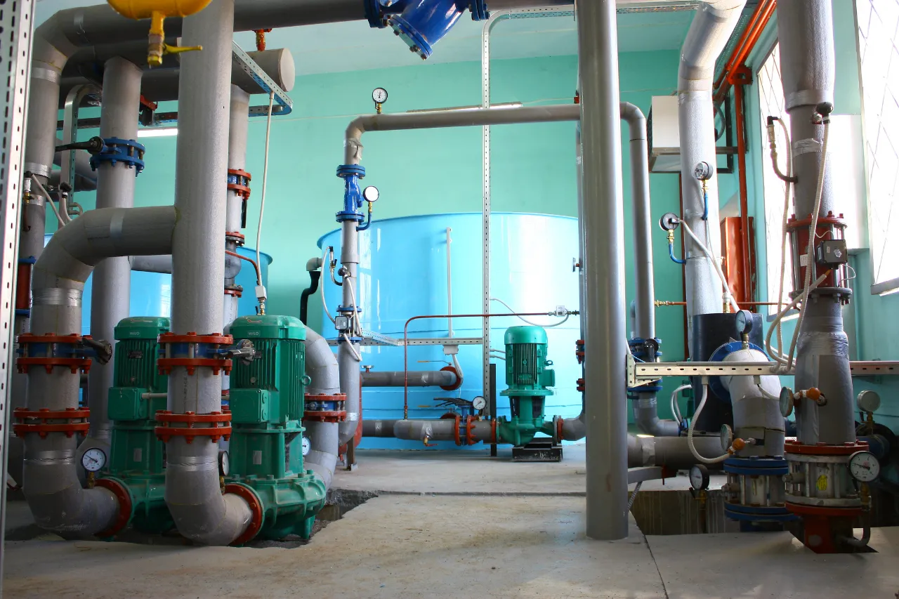 Impianto industriale con pompe, tubazioni e serbatoio blu