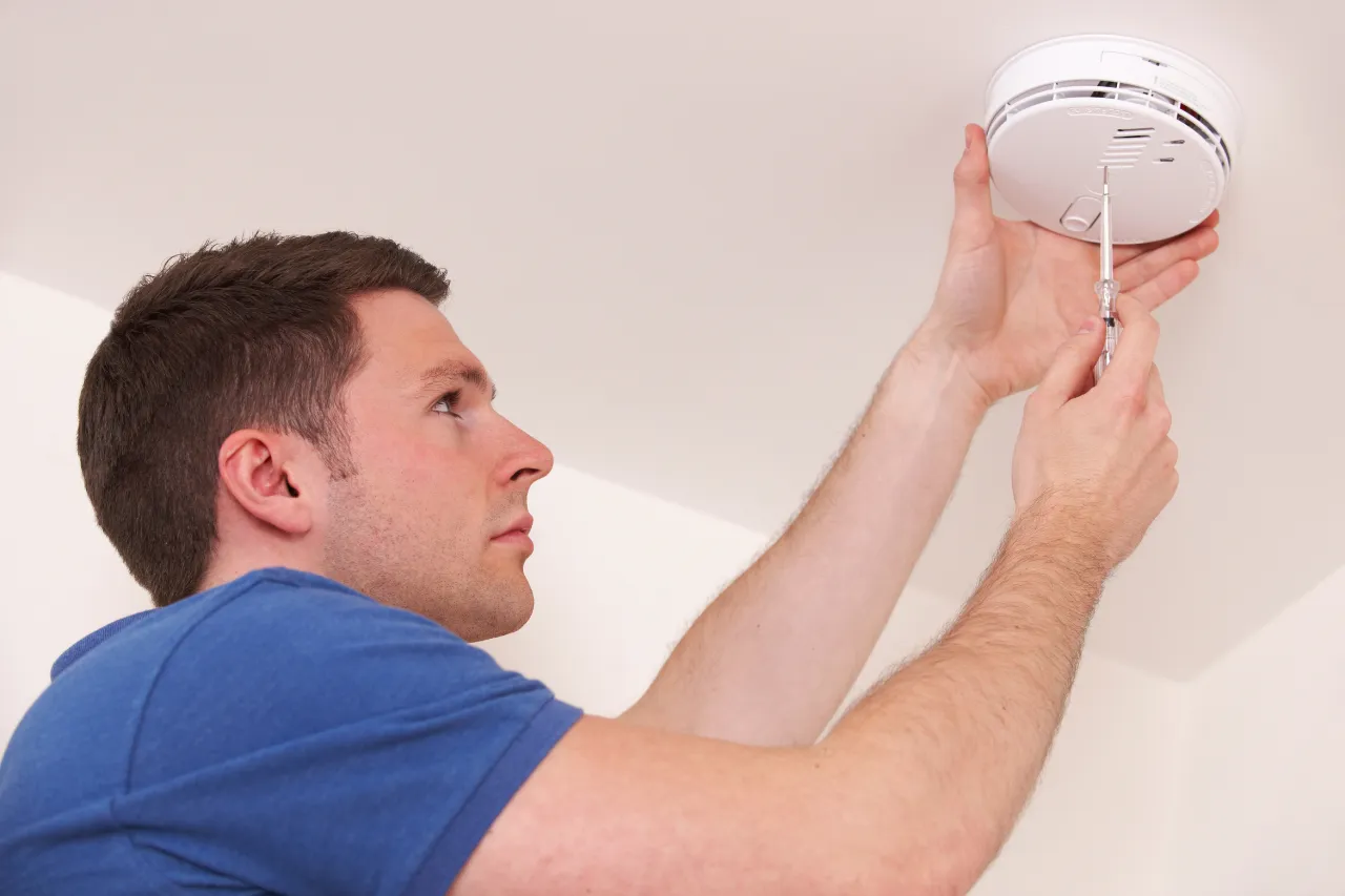 Uomo installa rilevatore di fumo al soffitto