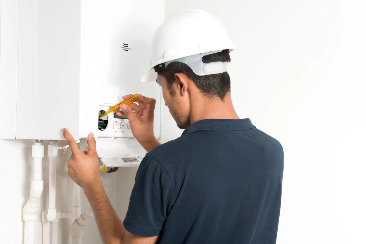 Tecnico controlla una caldaia murale con cacciavite