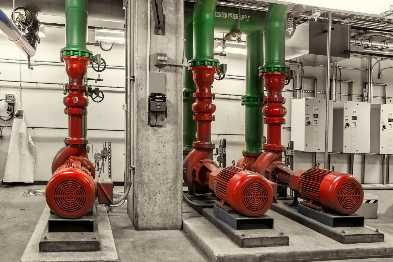 Tre pompe industriali rosse collegate a tubazioni verdi