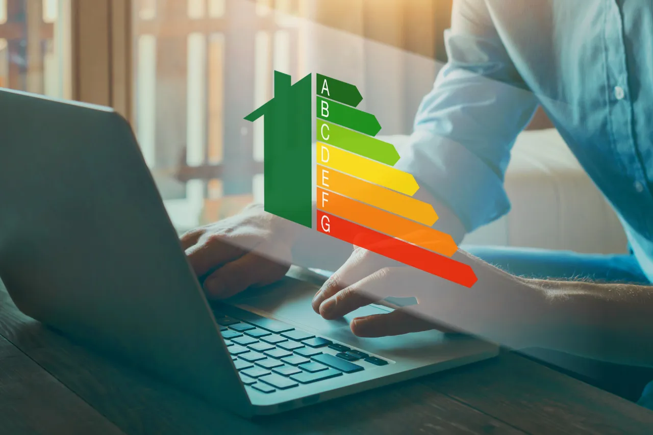 Persona al laptop con scala di efficienza energetica domestica