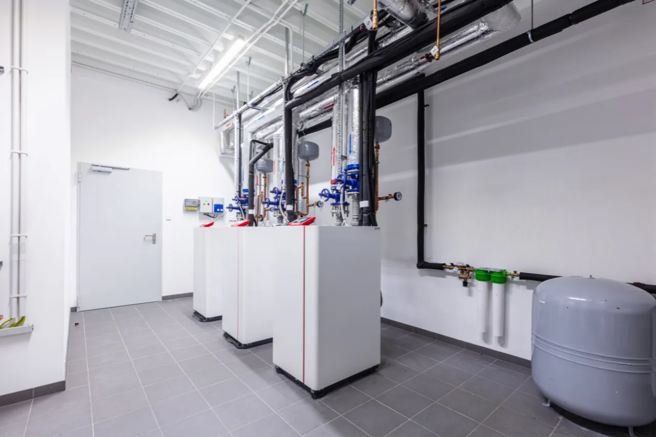 Locale tecnico con caldaie, tubazioni isolate e serbatoio