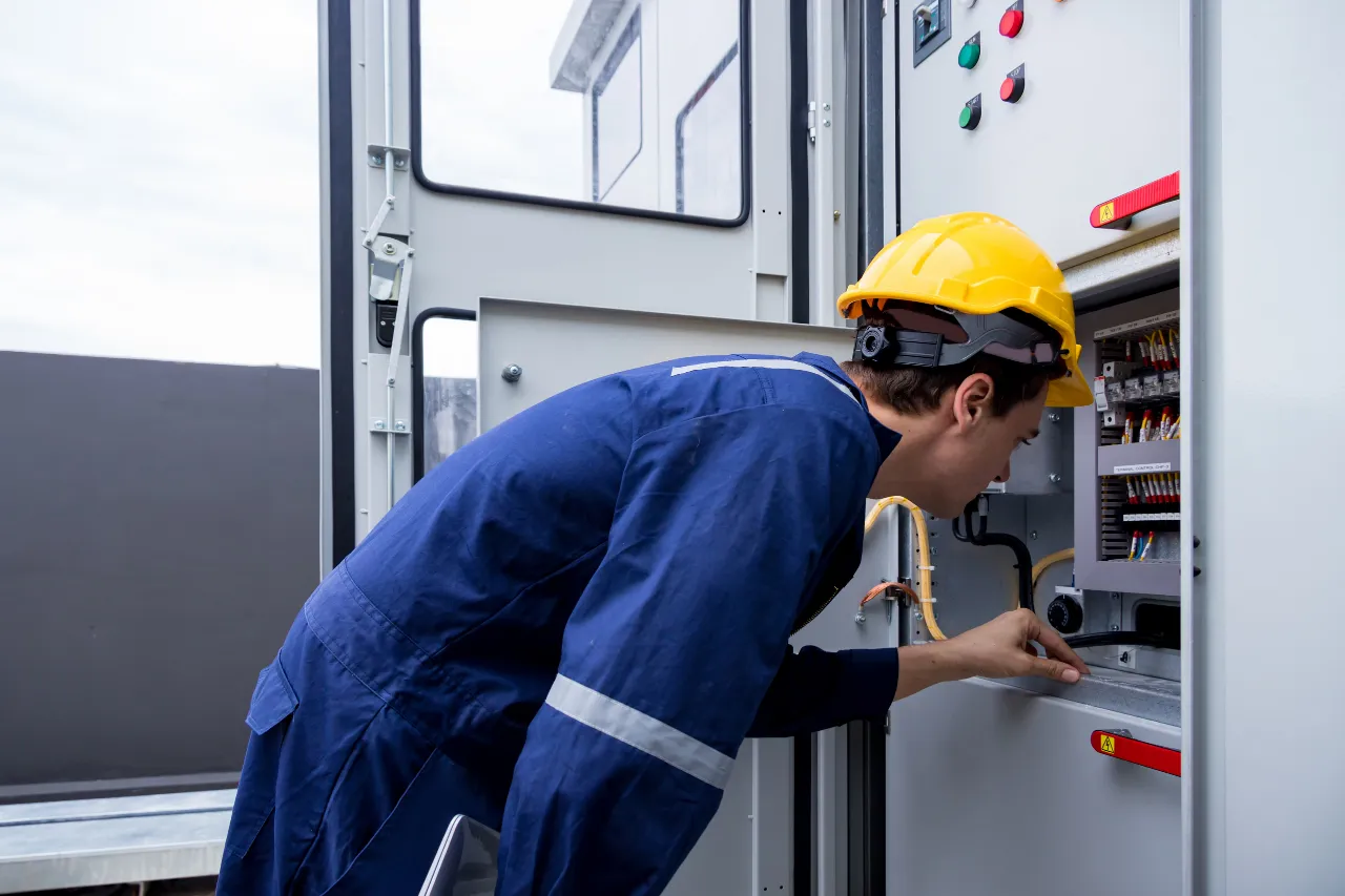 Tecnico con casco controlla un quadro elettrico industriale