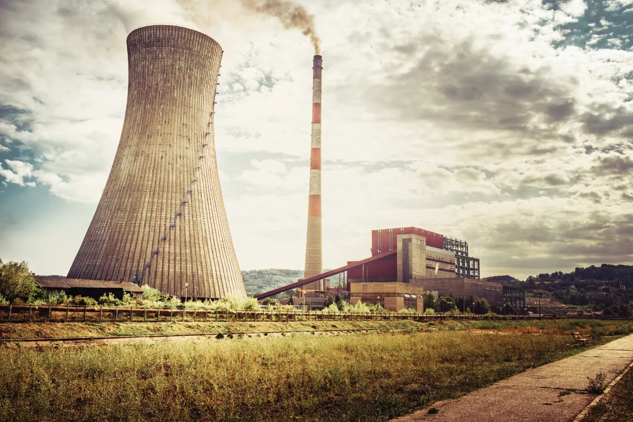 Centrale elettrica con torre di raffreddamento e ciminiera fumante