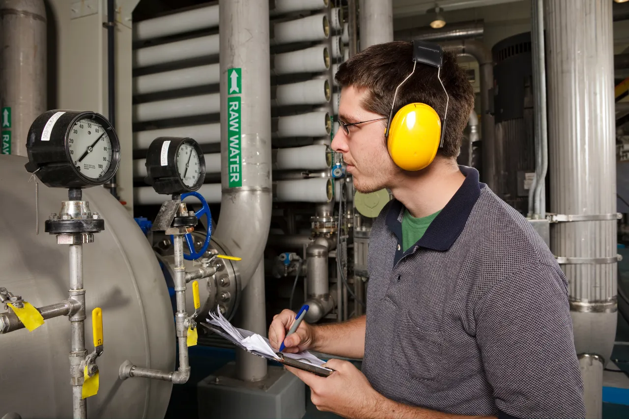 Tecnico controlla manometri in un impianto industriale