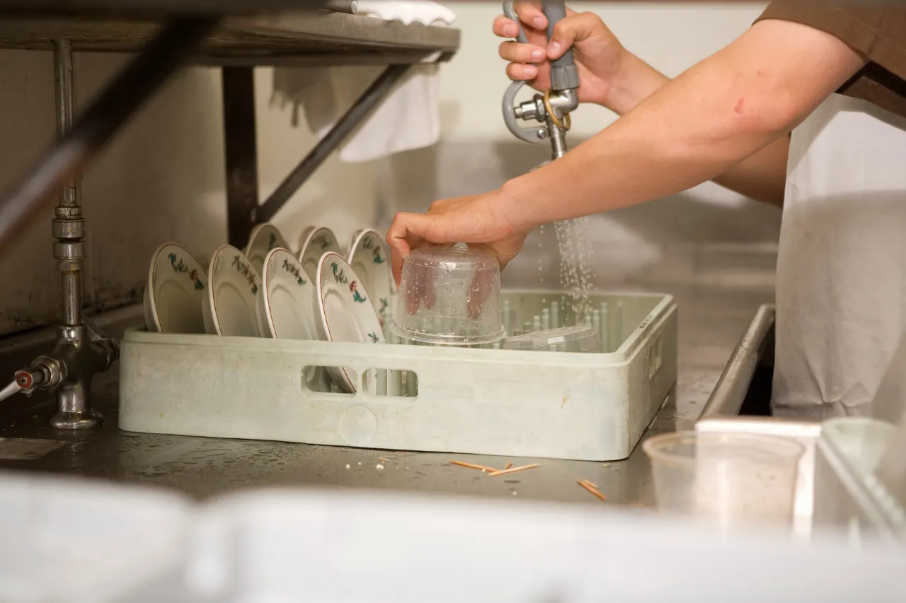 Addetto lava stoviglie in una cucina professionale