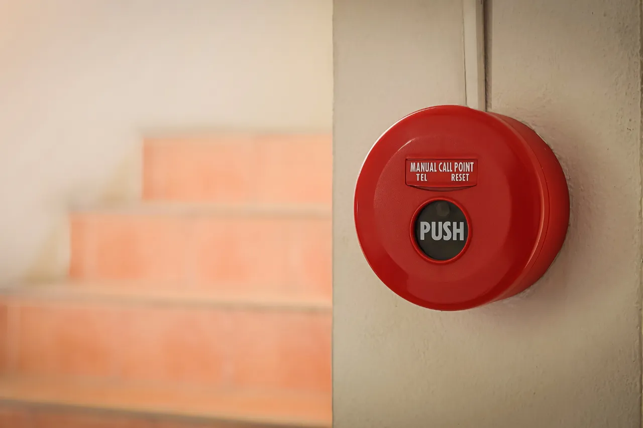 Pulsante rosso di allarme antincendio su parete