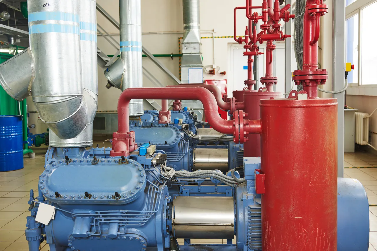 Compressori industriali blu con tubazioni rosse in sala tecnica