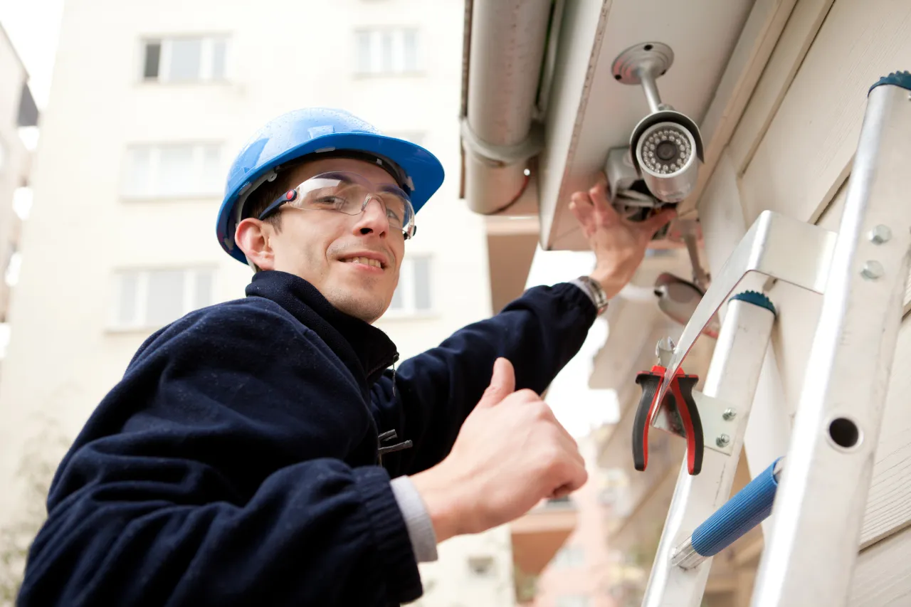 Tecnico installa telecamera di sicurezza su parete esterna