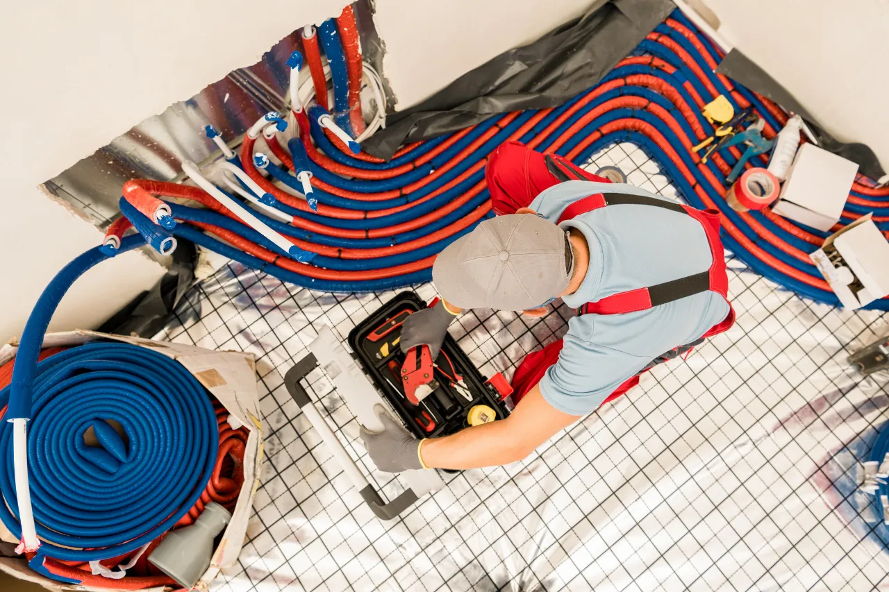 Tecnico installa tubazioni rosse e blu per impianto radiante