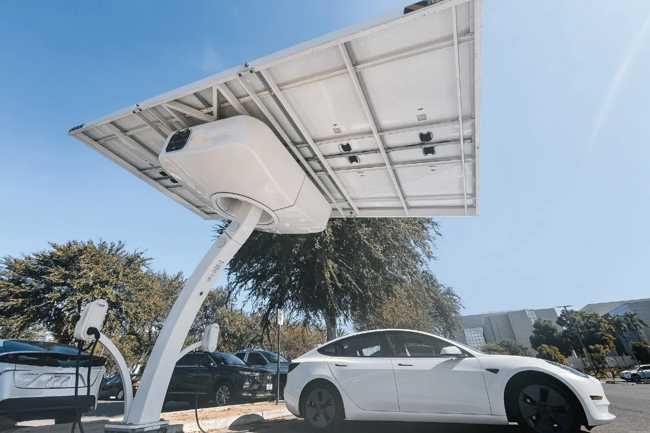 Auto elettrica bianca sotto pensilina solare di ricarica