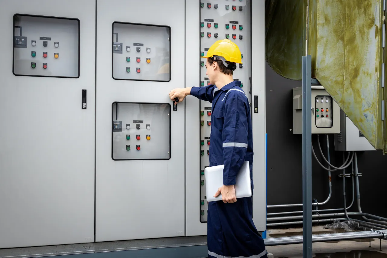 Tecnico con casco opera su quadro elettrico industriale