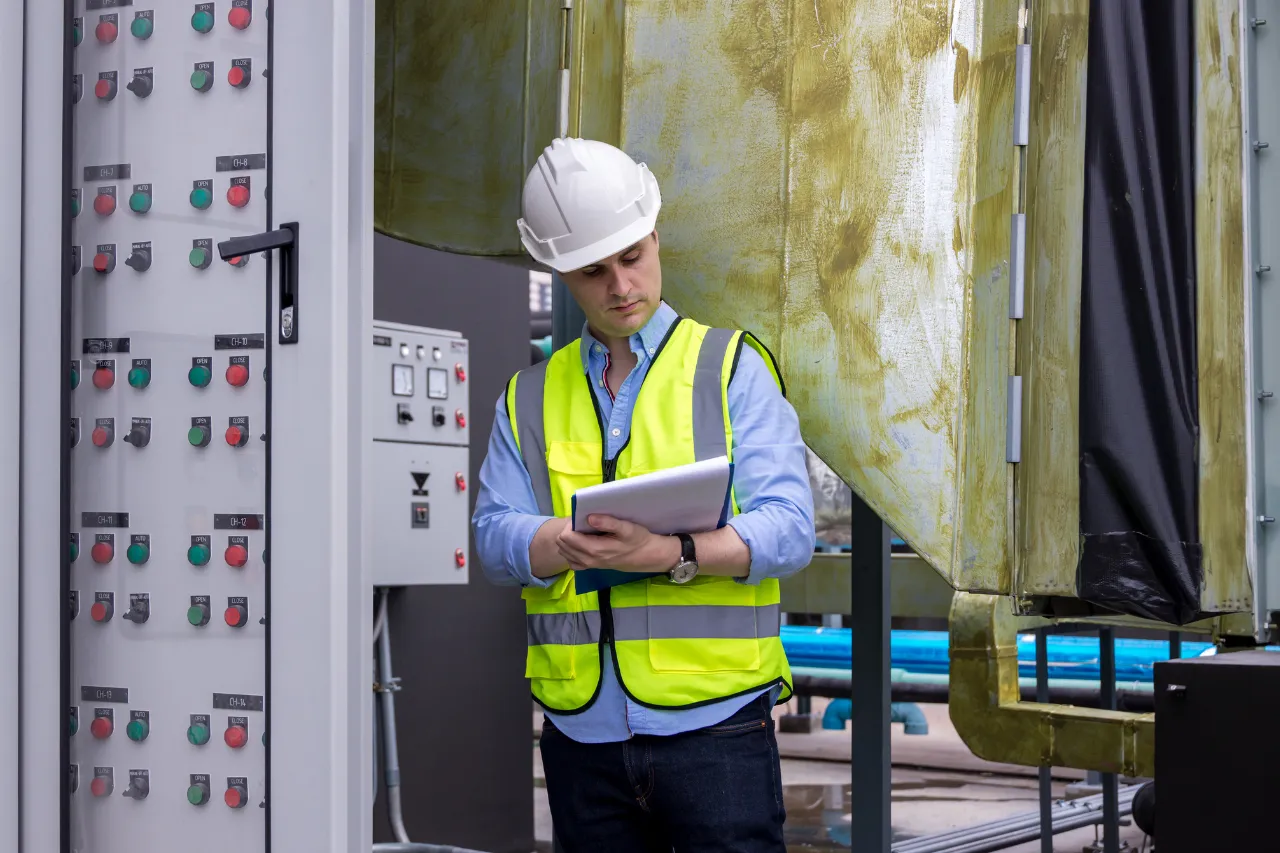 Tecnico controlla appunti accanto a un pannello industriale