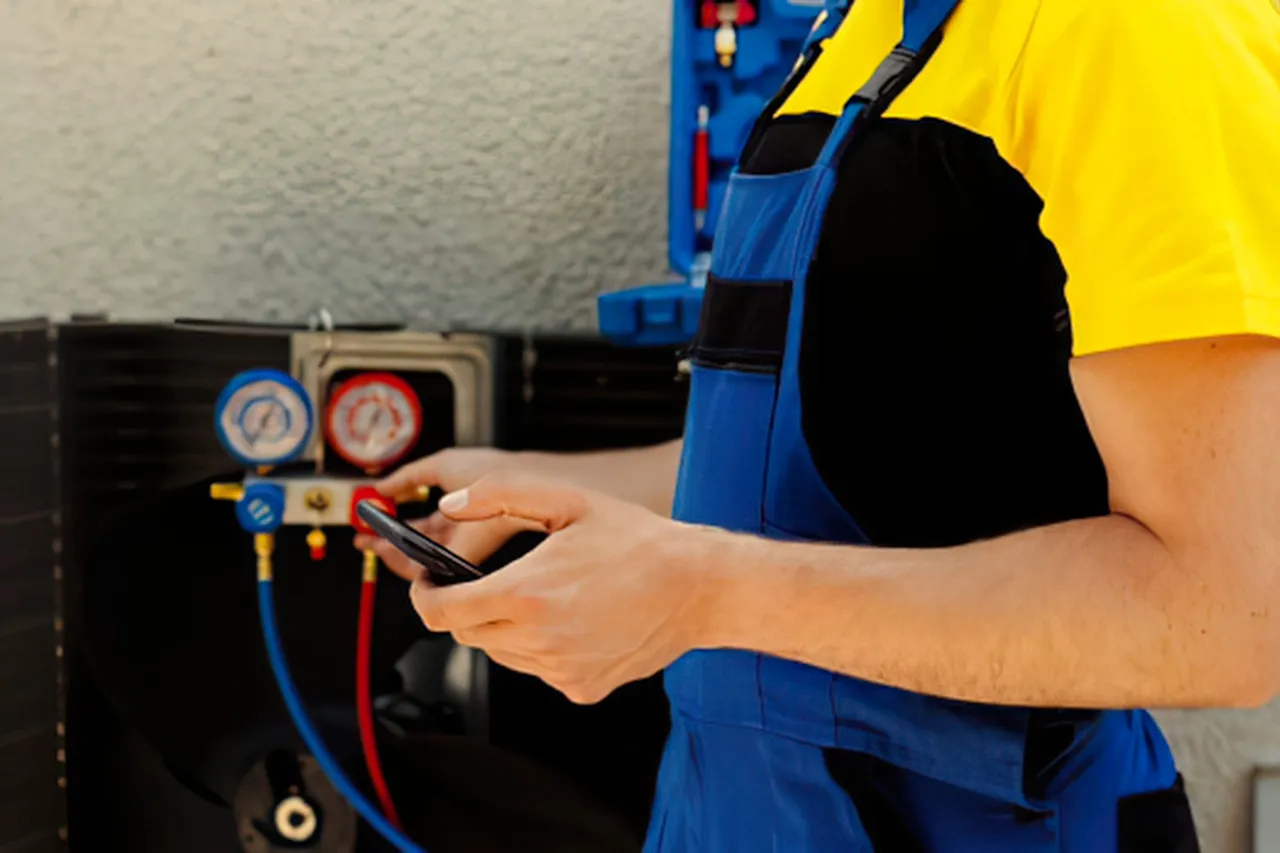 Tecnico HVAC usa smartphone vicino a manometri del climatizzatore
