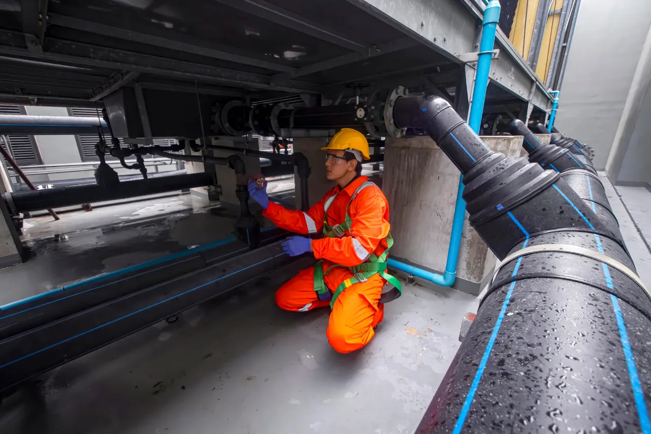 Tecnico ispeziona tubazioni industriali indossando dispositivi di sicurezza