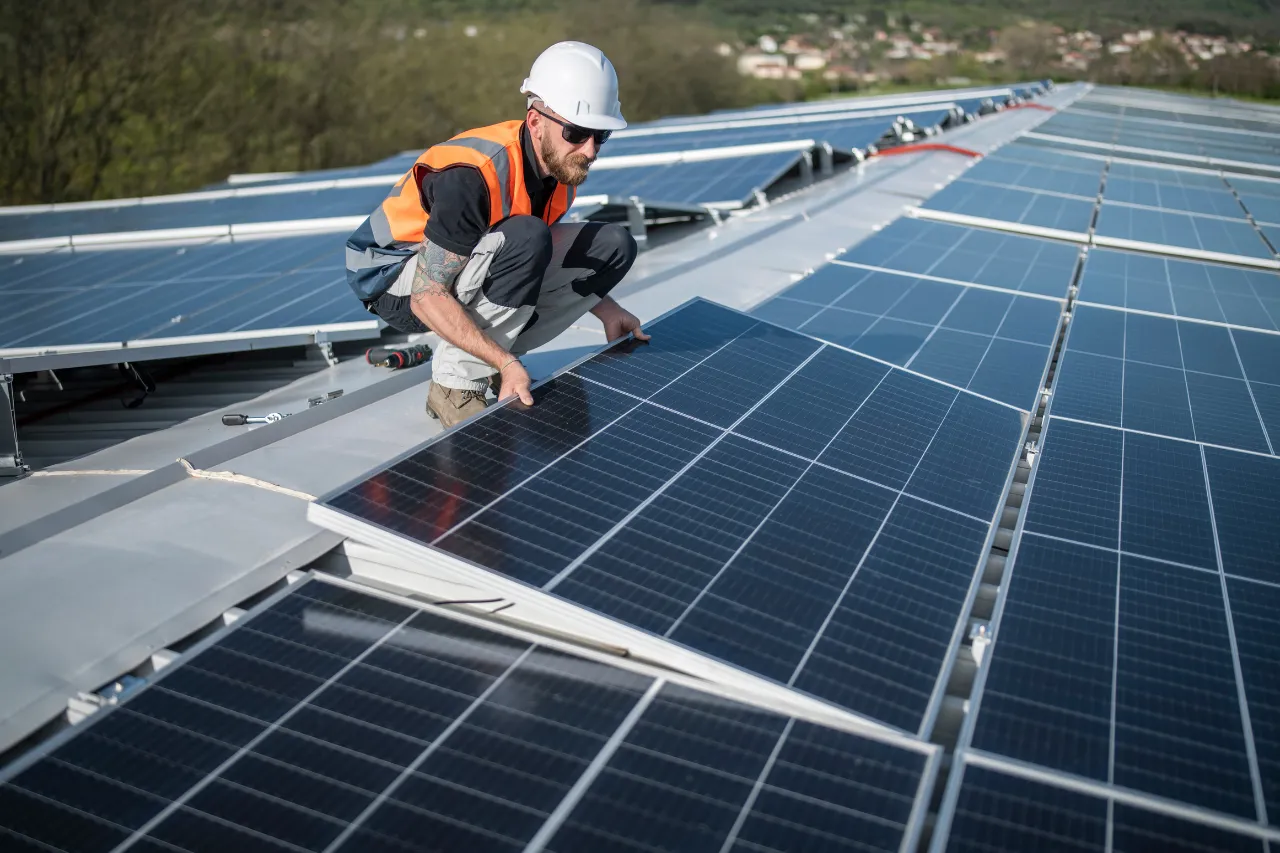 Tecnico installa pannello solare su tetto industriale
