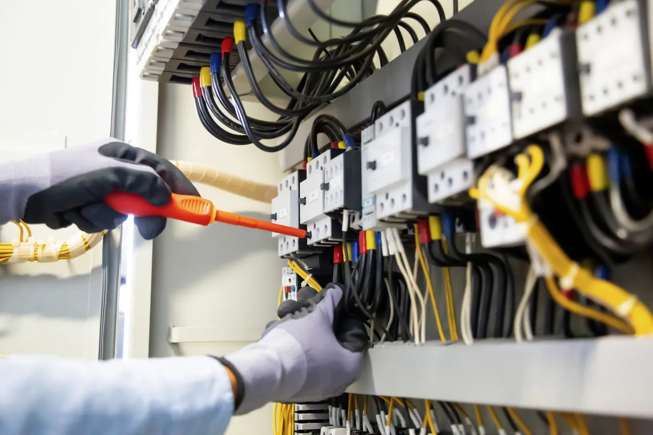 Tecnico controlla un quadro elettrico con cacciavite isolato