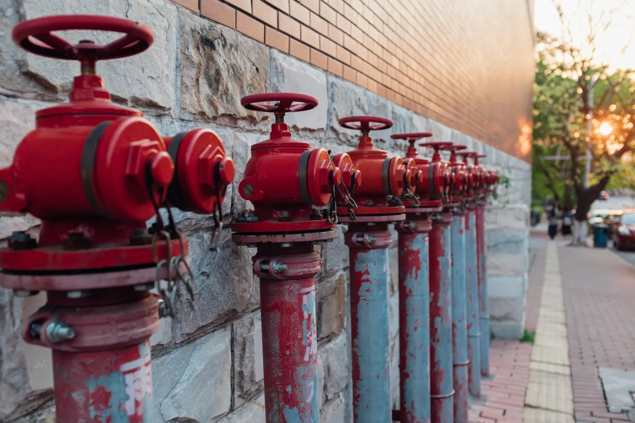 Fila di valvole antincendio rosse lungo un edificio