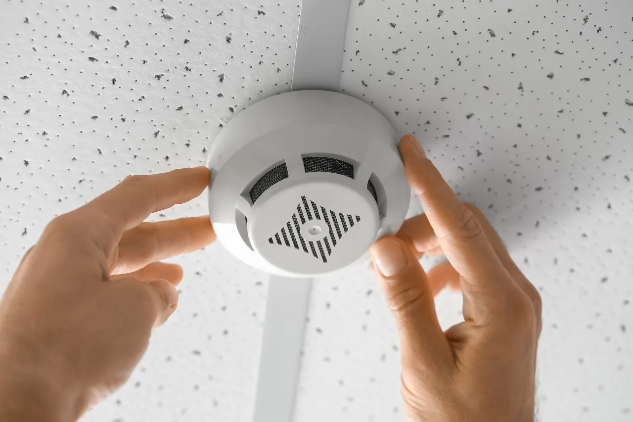 Mani installano un rilevatore di fumo sul soffitto