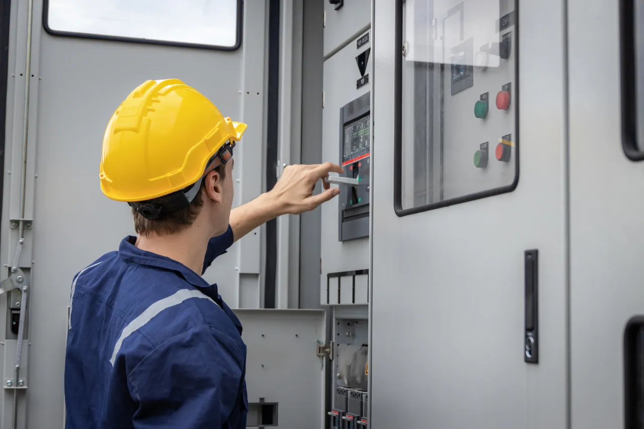 Tecnico con casco controlla quadro elettrico industriale