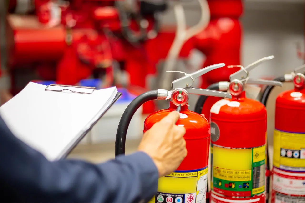Tecnico ispeziona estintori rossi con checklist