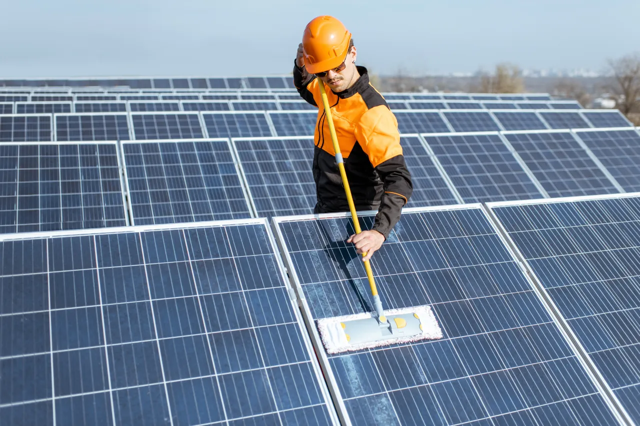 Tecnico pulisce pannelli solari in un impianto fotovoltaico