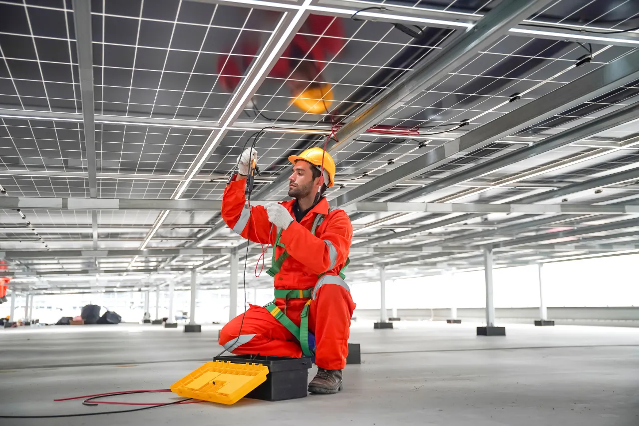 Tecnico installa cablaggi sotto pannelli solari