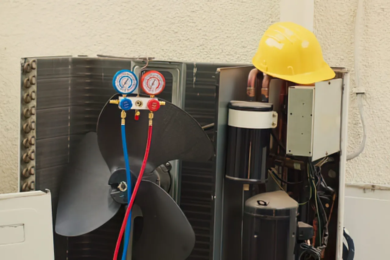 Tecnico ripara condizionatore con manometri e casco giallo