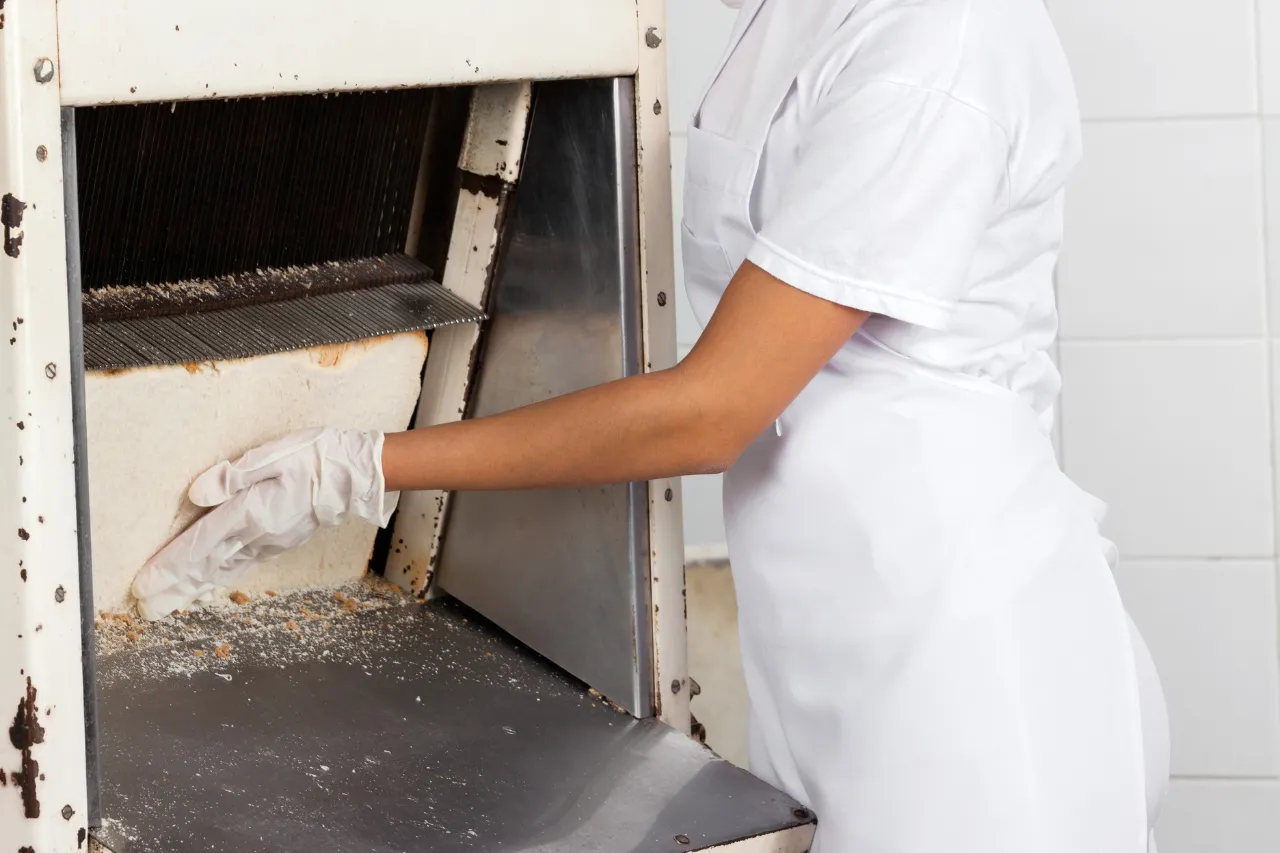 Addetta pulisce una macchina industriale per alimenti