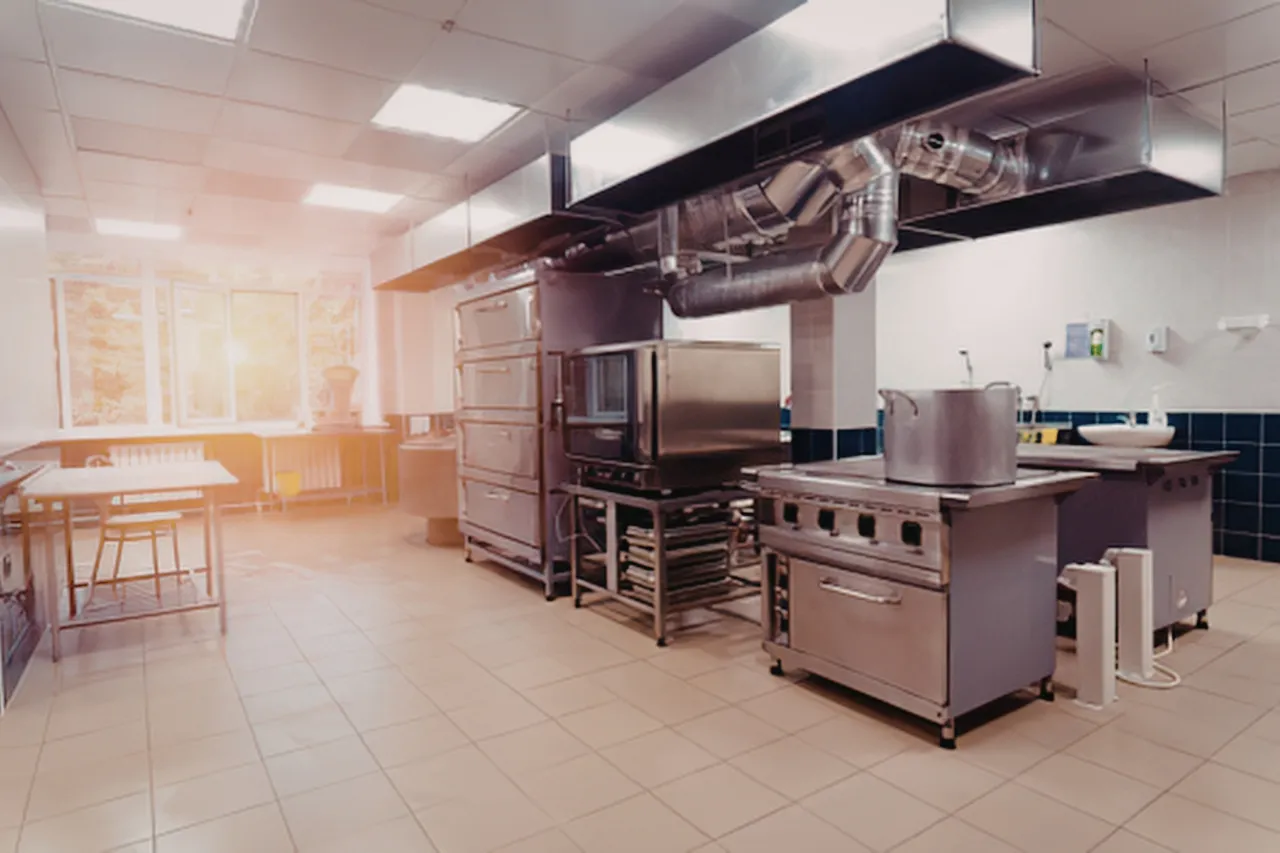 Cucina professionale con fornelli, forni e cappa aspirante