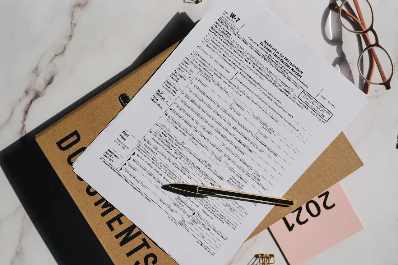 Modulo fiscale W-7 con penna, cartellina e occhiali