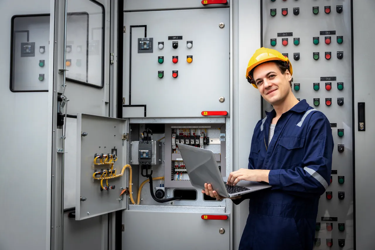 Tecnico con laptop davanti a quadro elettrico industriale