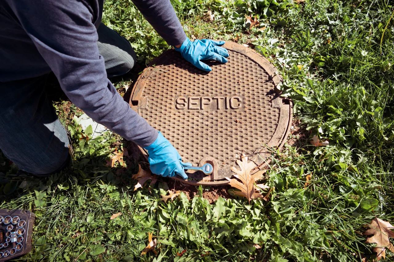 Tecnico apre tombino settico con chiave inglese