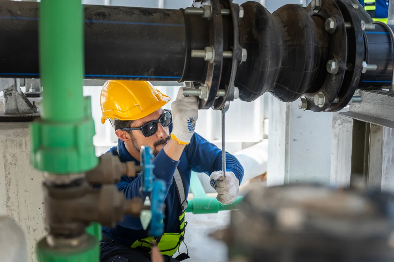 Tecnico ispeziona raccordo di tubazioni industriali