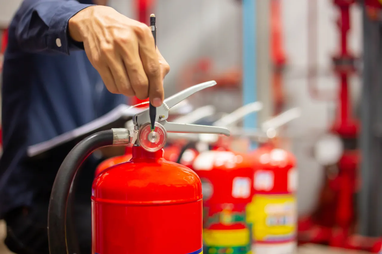 Tecnico controlla un estintore rosso con cacciavite