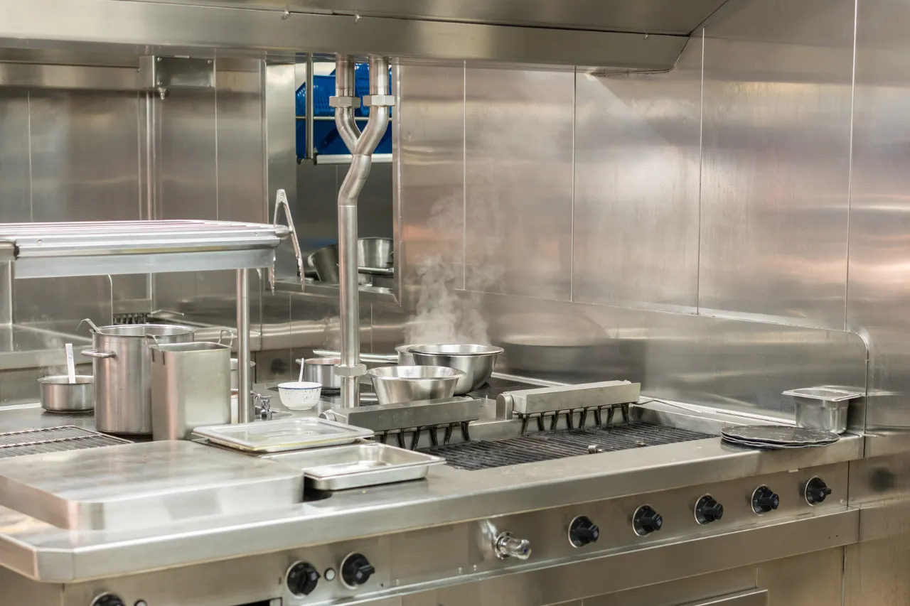 Cucina professionale in acciaio con fornelli e pentole