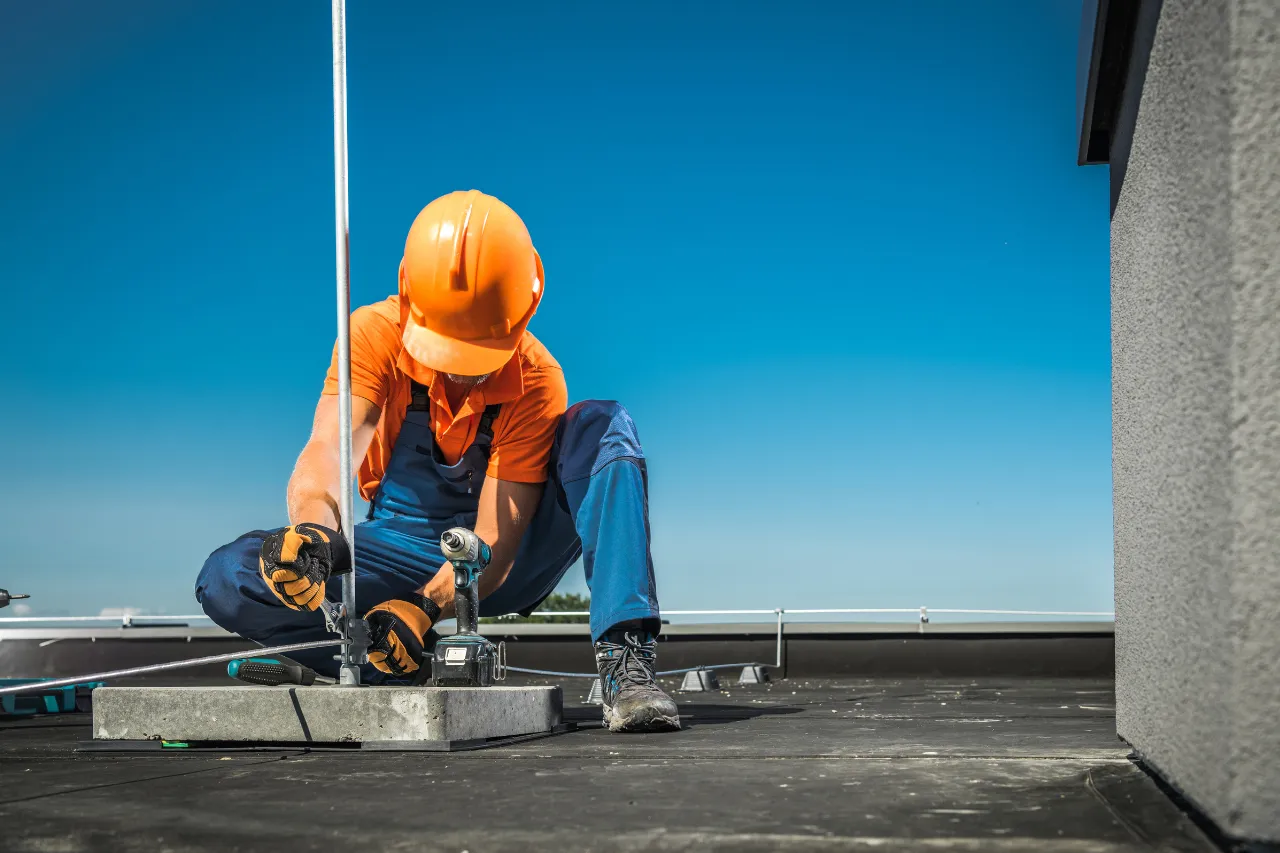 Operaio installa palo metallico sul tetto