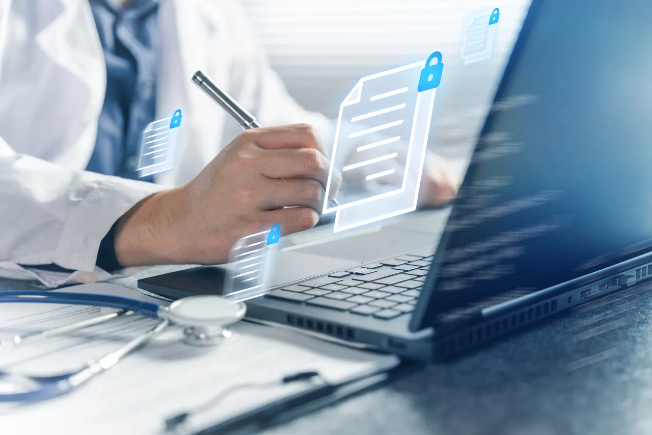 Medico al laptop con documenti digitali protetti
