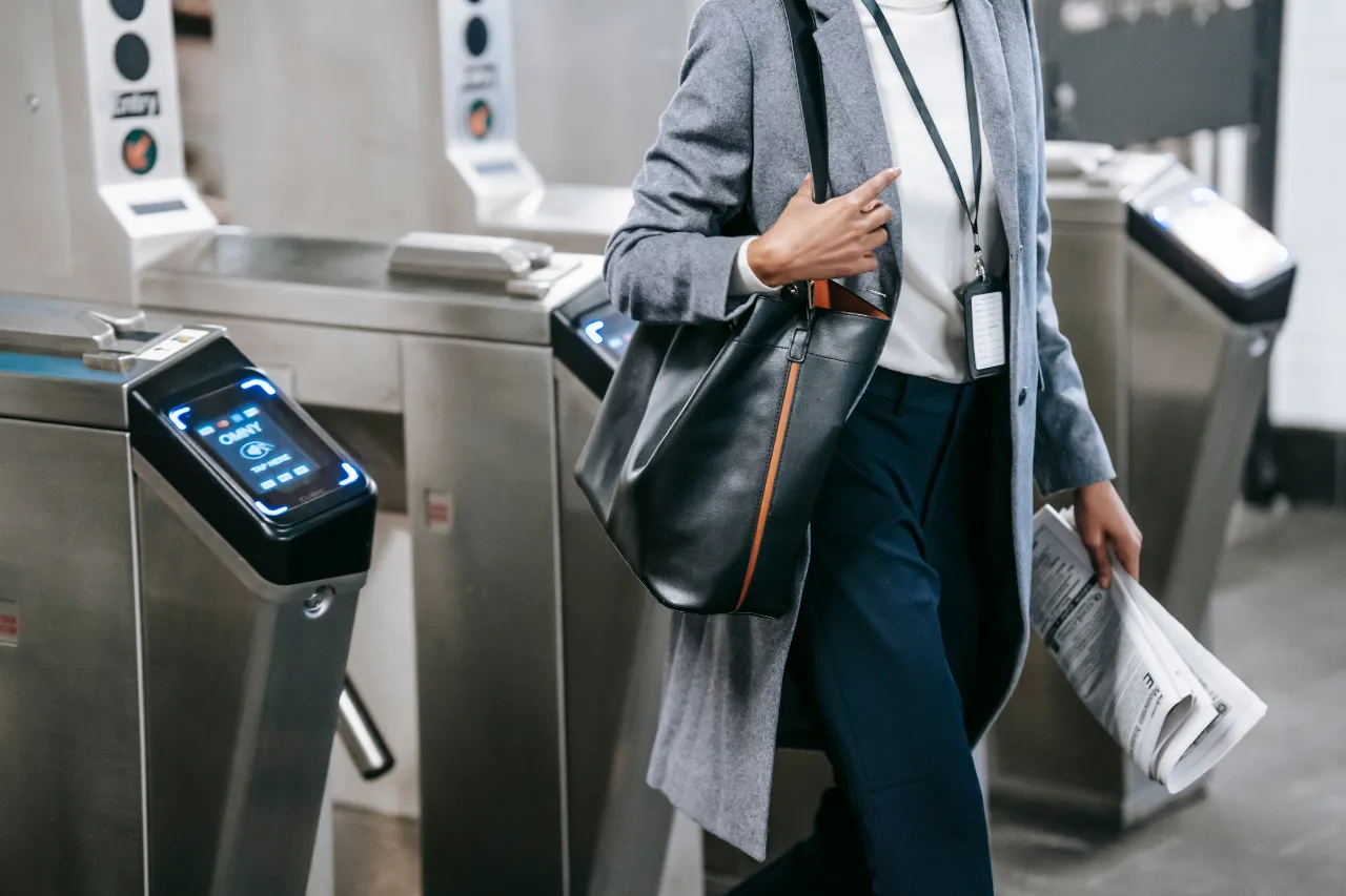 Pendolare attraversa i tornelli della metropolitana con borsa e giornale