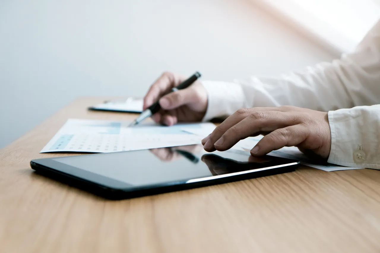 Persona usa tablet e compila documenti finanziari