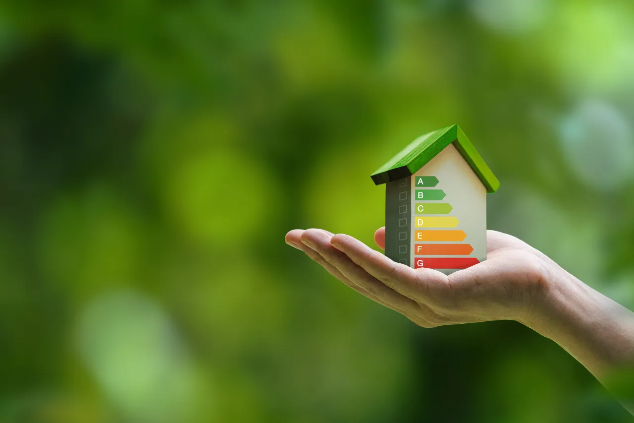 Mano sostiene casa con scala di efficienza energetica