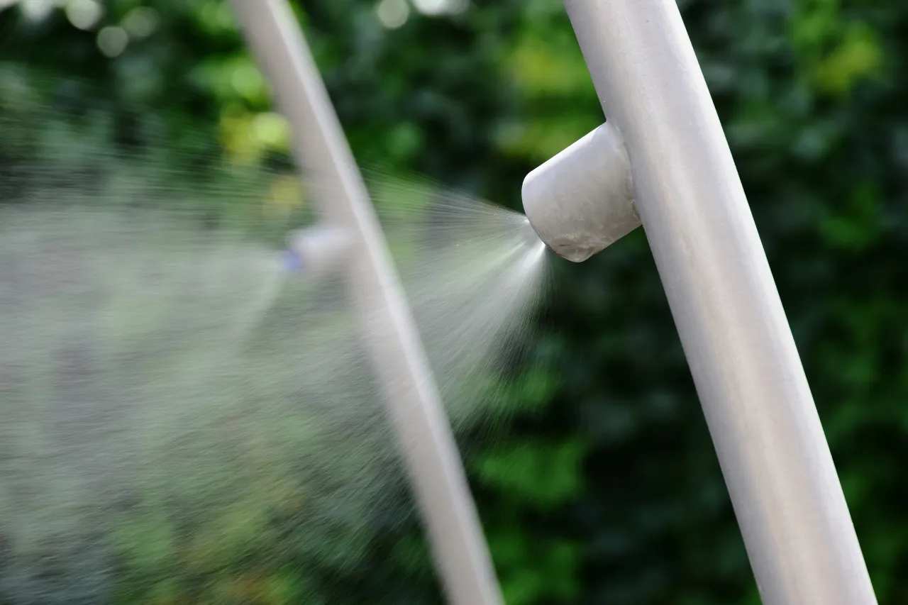 Ugello nebulizzatore spruzza acqua davanti a fogliame verde