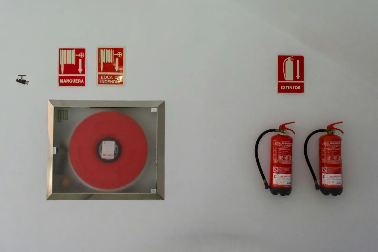 Idrante antincendio e due estintori su parete bianca