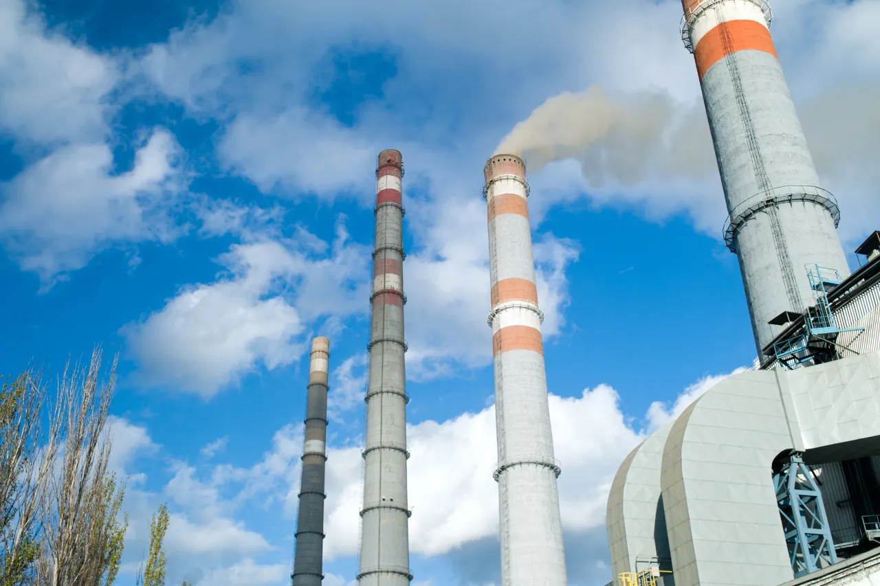 Ciminiere industriali con fumo sotto cielo azzurro