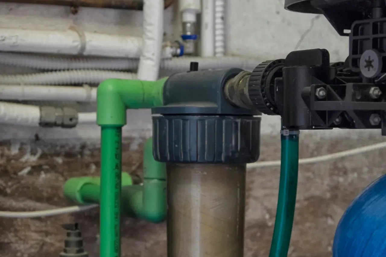 Filtro acqua collegato a tubazioni verdi in locale tecnico
