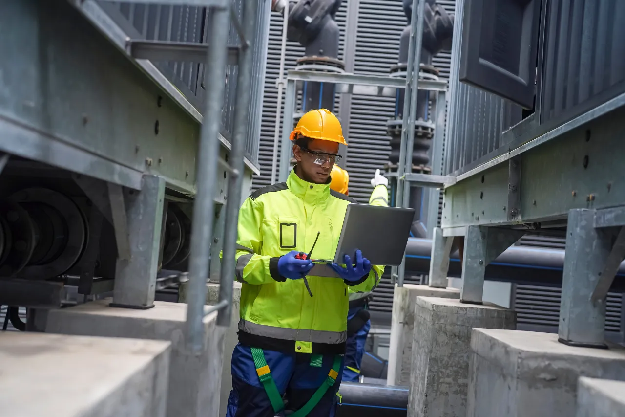 Tecnico con laptop ispeziona impianto industriale