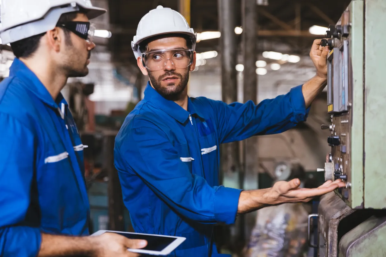 Due tecnici regolano un pannello di controllo industriale