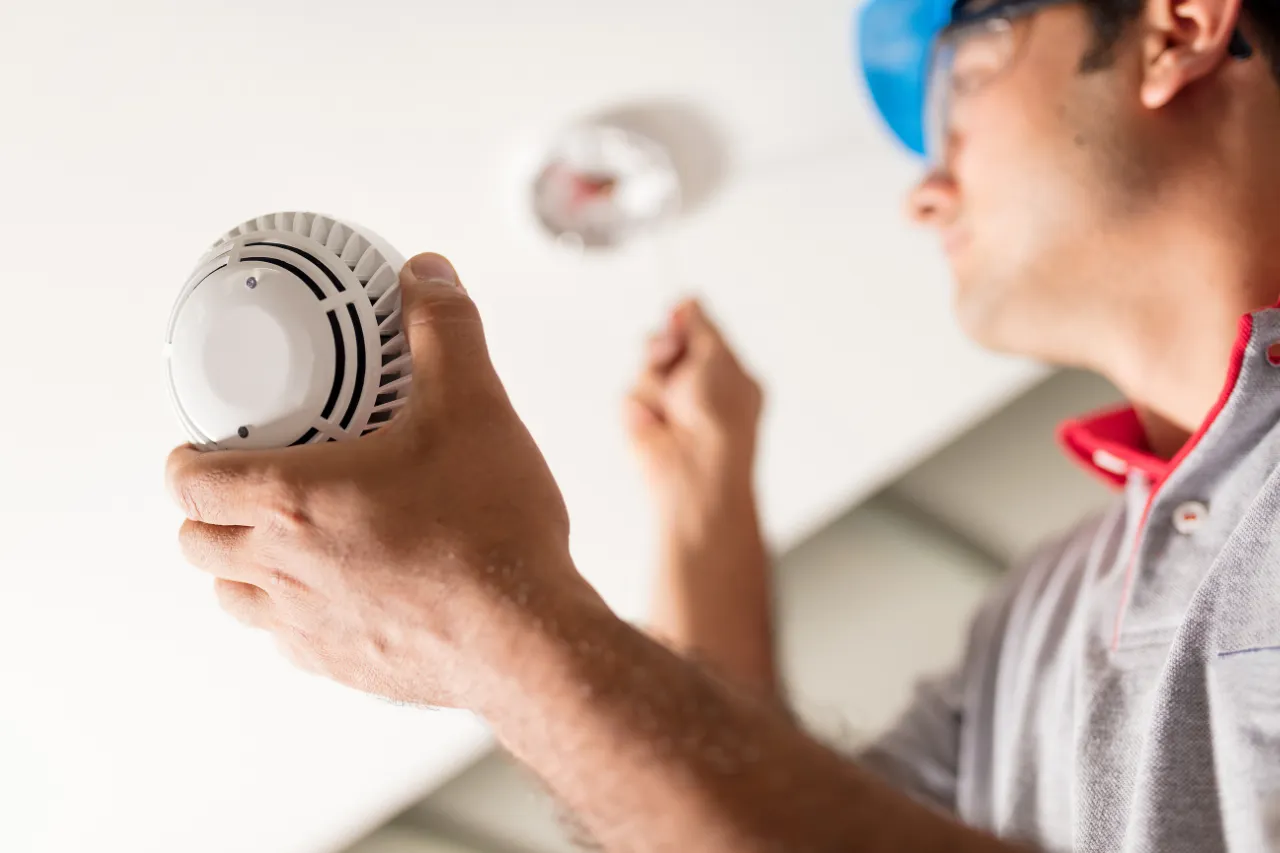 Tecnico installa un rilevatore di fumo sul soffitto